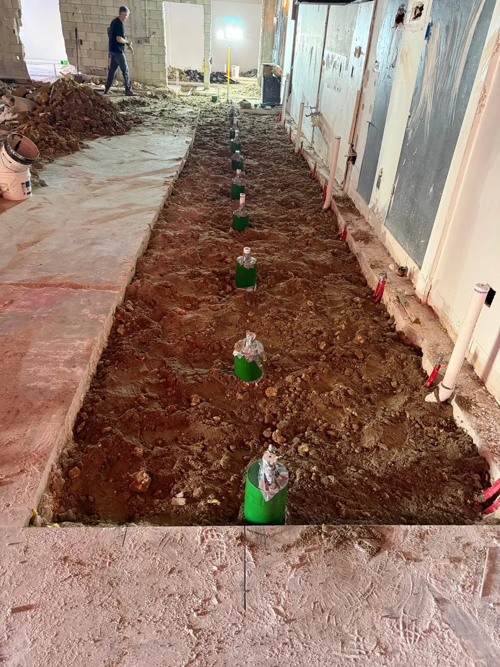 Underground plumbing rough-in trench with water and drain lines set for a new building